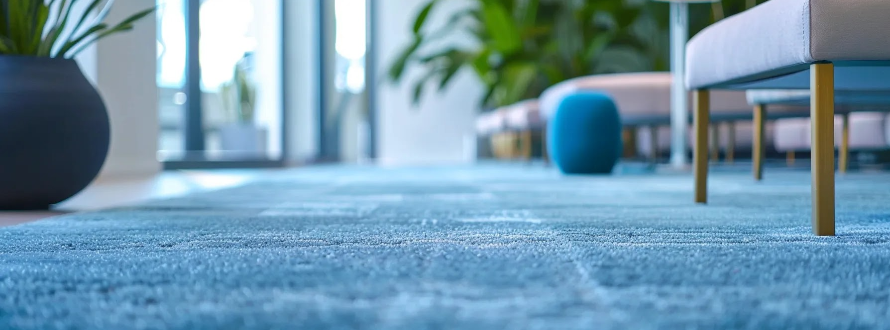 Blue commercial carpet in a modern office setting, featuring decorative plants and stylish furniture, emphasizing cleanliness and comfort in workplace environments.